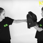 young girl hitting training pads with young boy helping