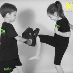 young girl kicking training pads with you boy helping